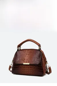 Detailed macro view of dark brown crocodile embossed leather and gold metal hardware trim