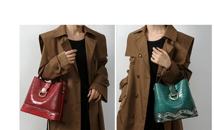 Detail view of crocodile embossed bucket bags with snake print base and golden D-buckle