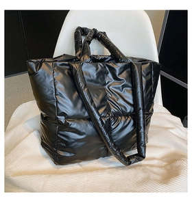 Detail shot of black quilted puffer tote bag on a modern white chair with glossy nylon texture