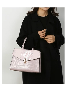 Borsa rosa effetto coccodrillo e serpente indossata da modella con cappotto nero