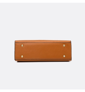 Detail view of brown handbag base with protective gold metal studs and neat black stitching