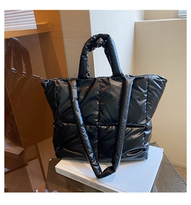 Close-up of quilted puffy tote bag with glossy black finish and dual shoulder straps