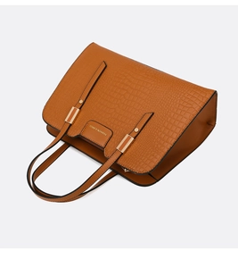 Detail of brown crocodile embossed tote bag showing refined leather texture and metal buckle