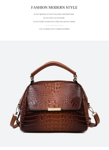 Detail of dark brown crocodile embossed leather handbag with golden metal hardware