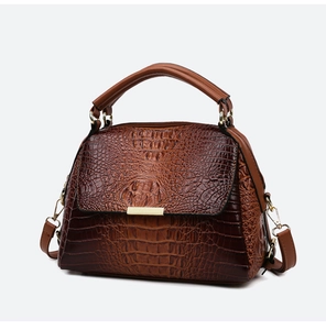 Detailed macro view of dark brown crocodile pattern leather handbag with gold metal clasp