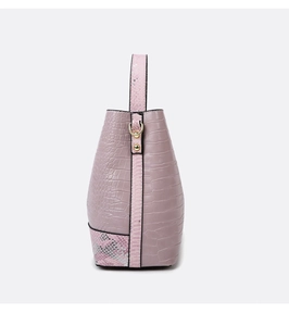 Detail of pink faux crocodile and snake texture on a stylish bucket bag with gold rings