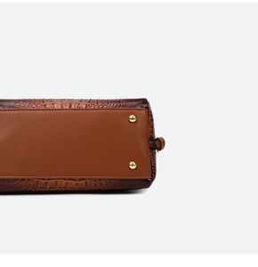 Close-up of brown crocodile embossed leather handbag with protective gold metal feet