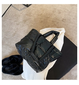Detail shot of black quilted down tote bag with a glossy finish and soft padded handles