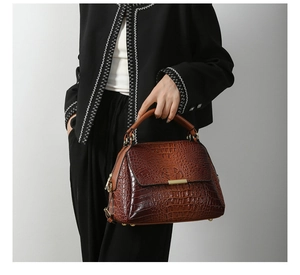 Detail of vintage brown crocodile texture and gold hardware on a leather handbag