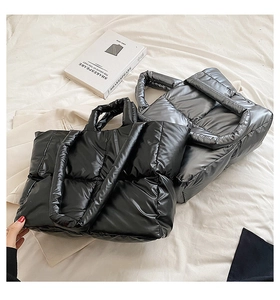 Detail of large quilted tote bags in glossy black and silver with down-like texture