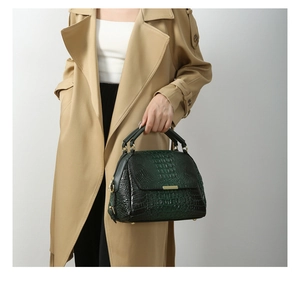 Detailed view of dark green crocodile pattern handbag with elegant gold metal hardware