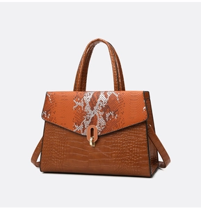 Dettaglio borsa marrone con texture a coccodrillo, patta a serpente e chiusura oro