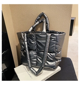 Detail of silver metallic quilted puffer tote bag on a white decorative book display