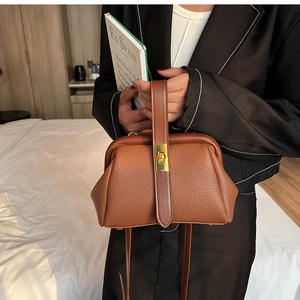 Detail of brown litchi pattern leather bag with gold metal clasp and adjustable strap
