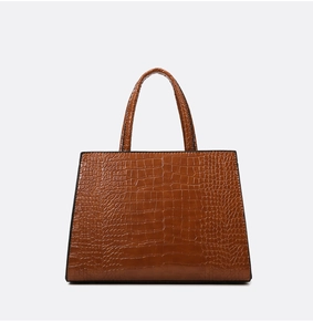 Dettaglio della trama a coccodrillo marrone e del manico di una borsa a mano da donna