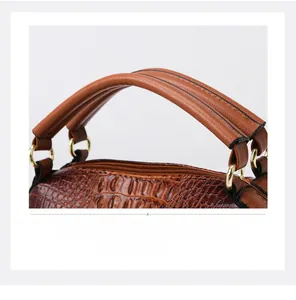 Detailed view of crocodile embossed leather handbag with golden hardware and top handles
