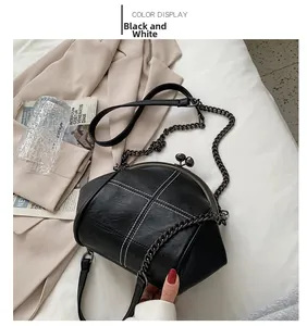 Detail of retro black leather shell bag with white cross stitching and metal ball clasp