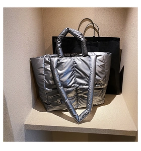 Macro detail of metallic silver quilted tote bag with soft down padding and shoulder strap