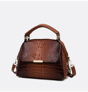 Close-up of brown crocodile texture leather handbag with gold metal clasp detail
