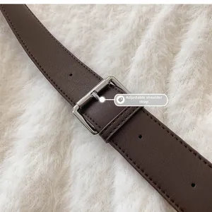 Gros plan sur une bandoulière en cuir marron foncé avec boucle argentée et couture fine