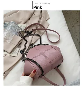 Pink shell crossbody bag with quilted stitching and vintage clasp on a white background