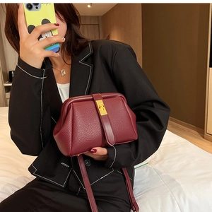 Detail of burgundy lychee leather doctor bag with golden twist lock and slim strap