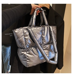Detail of silver quilted puffer tote bag with metallic texture and carry handles