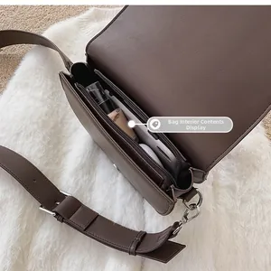 Compartiment interne du sac bandoulière en cuir marron foncé avec téléphone et rouge à lèvres