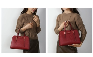 Detail of dark red crocodile embossed leather handbag with elegant gold metal hardware
