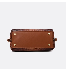 Detail view of the crocodile embossed leather handbag base with gold metal protective studs
