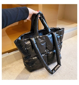 Detail of black puffer tote bag showing glossy quilted nylon texture and plush padding
