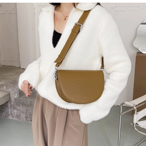 Gros plan d'un sac besace en cuir marron avec détails argentés et bandoulière large