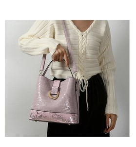 Detailed view of lavender crocodile pattern bucket bag with snake skin base and gold hardware