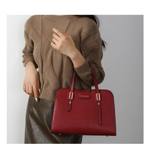 Close-up of deep red crocodile embossed PU leather handbag with gold logo plate