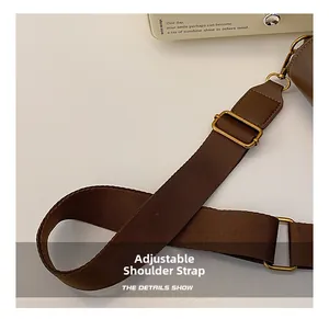 Detail of adjustable brown nylon shoulder strap with premium gold-tone metal hardware