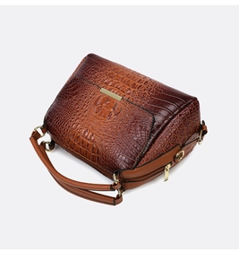 Detailed macro view of the brown crocodile pattern texture and gold hardware on handbag