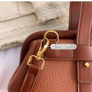 Close-up of premium golden metal hook and textured brown leather on handbag