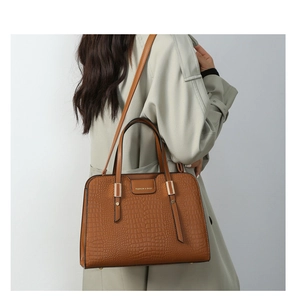 Brown crocodile embossed tote bag detail with double handles and long strap on a model