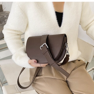 Détail du sac selle marron café avec boucle argentée et texture en cuir synthétique