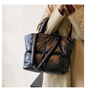 Close-up of black quilted puffer tote bag with glossy finish and thick padded handles