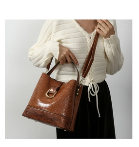 Brown crocodile texture bucket bag with gold U-buckle and snake print base on model