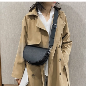 Détail d'un sac besace noir avec une large bandoulière et une boucle en métal argenté
