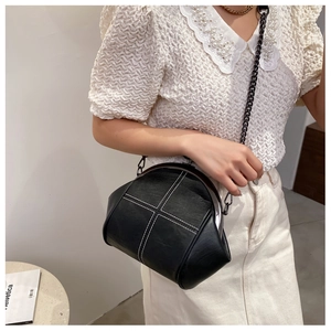 Detail of black PU shell bag featuring white contrast stitching and dark metal chain strap