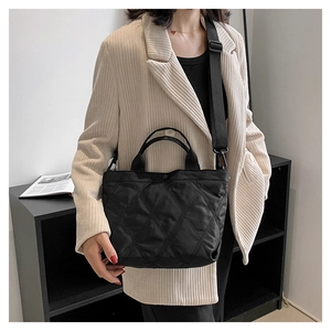 Borsa tote trapuntata nera con tracolla larga indossata da una modella in stile moderno