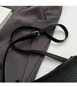 Detail of adjustable black leather strap with silver metal buckle on pleated pillow bag