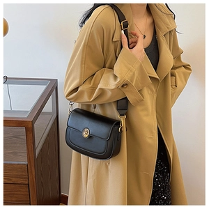 Detail of a black square leather bag with a vintage gold metal buckle and wide strap