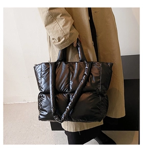 Detail of glossy black quilted down tote bag showing short handles and long shoulder straps