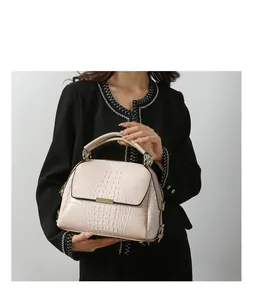 Model holding a beige crocodile-patterned handbag with golden metal hardware detail