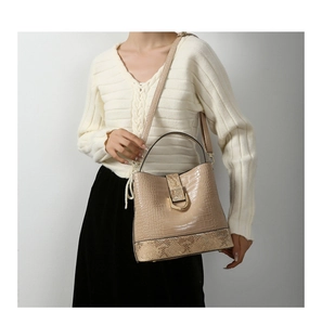 Detail of beige faux crocodile and snakeskin embossed tote with metal buckle clasp
