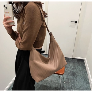 Détail de la texture d'un sac cabas en maille plissée beige porté à l'épaule en situation